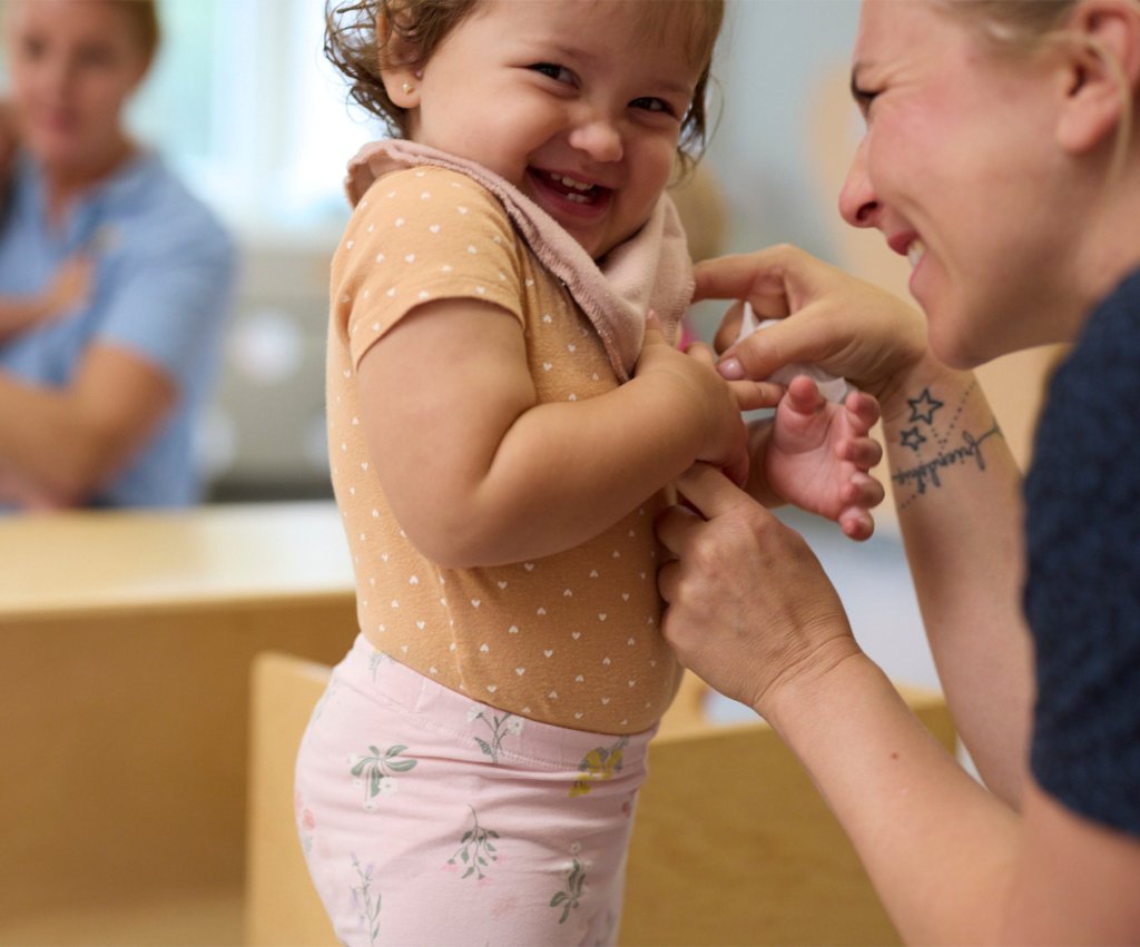 Little girl chuckling as she's getting tickled by educator of KiddieLand.