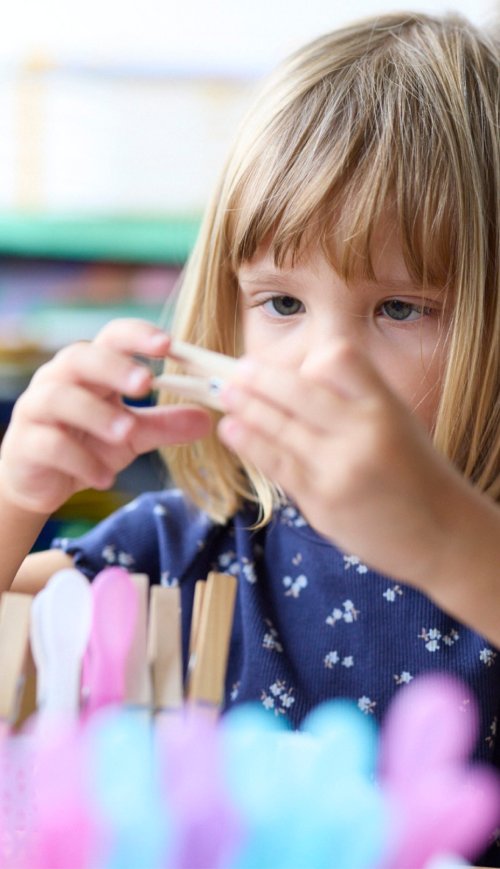 Little, blonde-haired girl doing arts and crafts at KiddieLand.