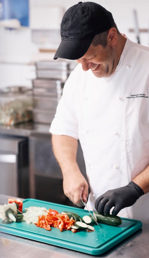 Pavlos, kitchen Chef at KiddieLand, cutting vegetables in the kitchen.