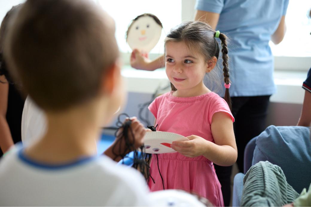 girl looking cheeky at daycare holding something they made